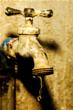 Old rusty water tap against textured wall.