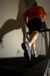 Person running on a treadmill, shadow visible.