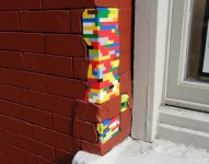 Brick wall repaired with colorful LEGO bricks.