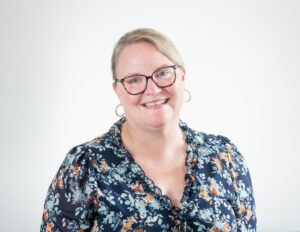 Smiling woman wearing glasses and floral blouse.