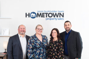 A group of people standing in front of the hometown property sales logo.